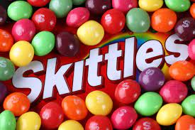 A Skittles bag with skittles around it;