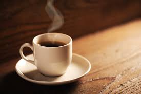 A white coffee cup sitting on a saucer that is on a brown table;