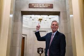 Kevin McCarthy standing in front of the Speaker of the House sign ;