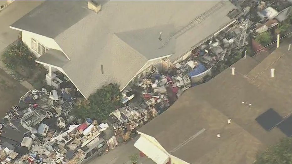 LA House of Hoarders with furniture and other trash piled on the front yard;