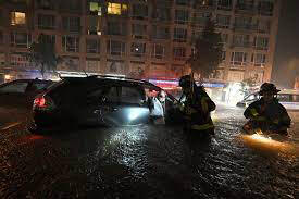 Firemen rescuing people in their cars from the flood waters;