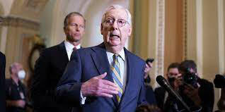 Mitch McConnell talking to the press in the Senate halls;