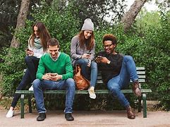 Friends Sitting On A Park Bench Tweeting;