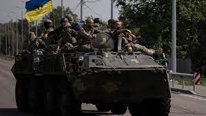 Ukrainian soldiers in a tank with the Ukrainian flag;